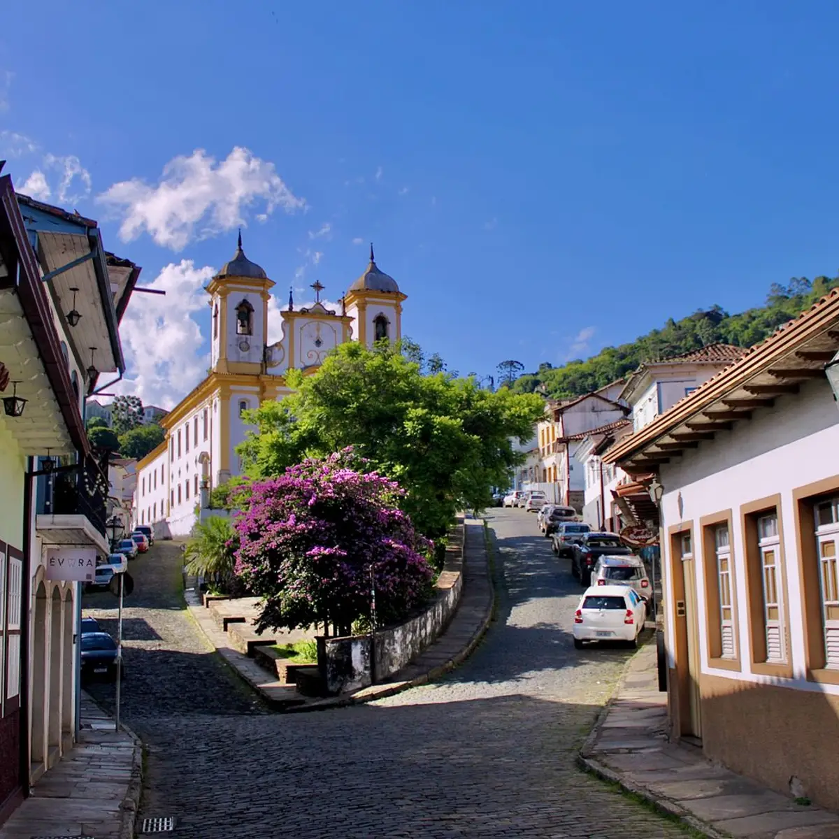 Ladeira de pedra com casarões coloniais e igreja ao fundo, em Ouro Preto